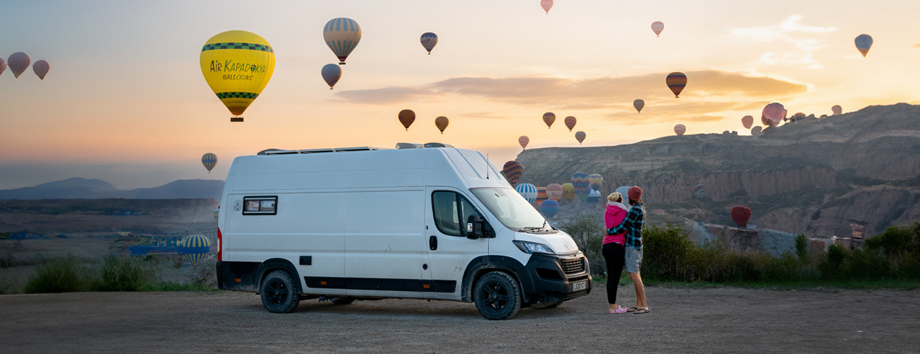 Campervan parked overlooking hot air balloons in Cappadocia at sunrise